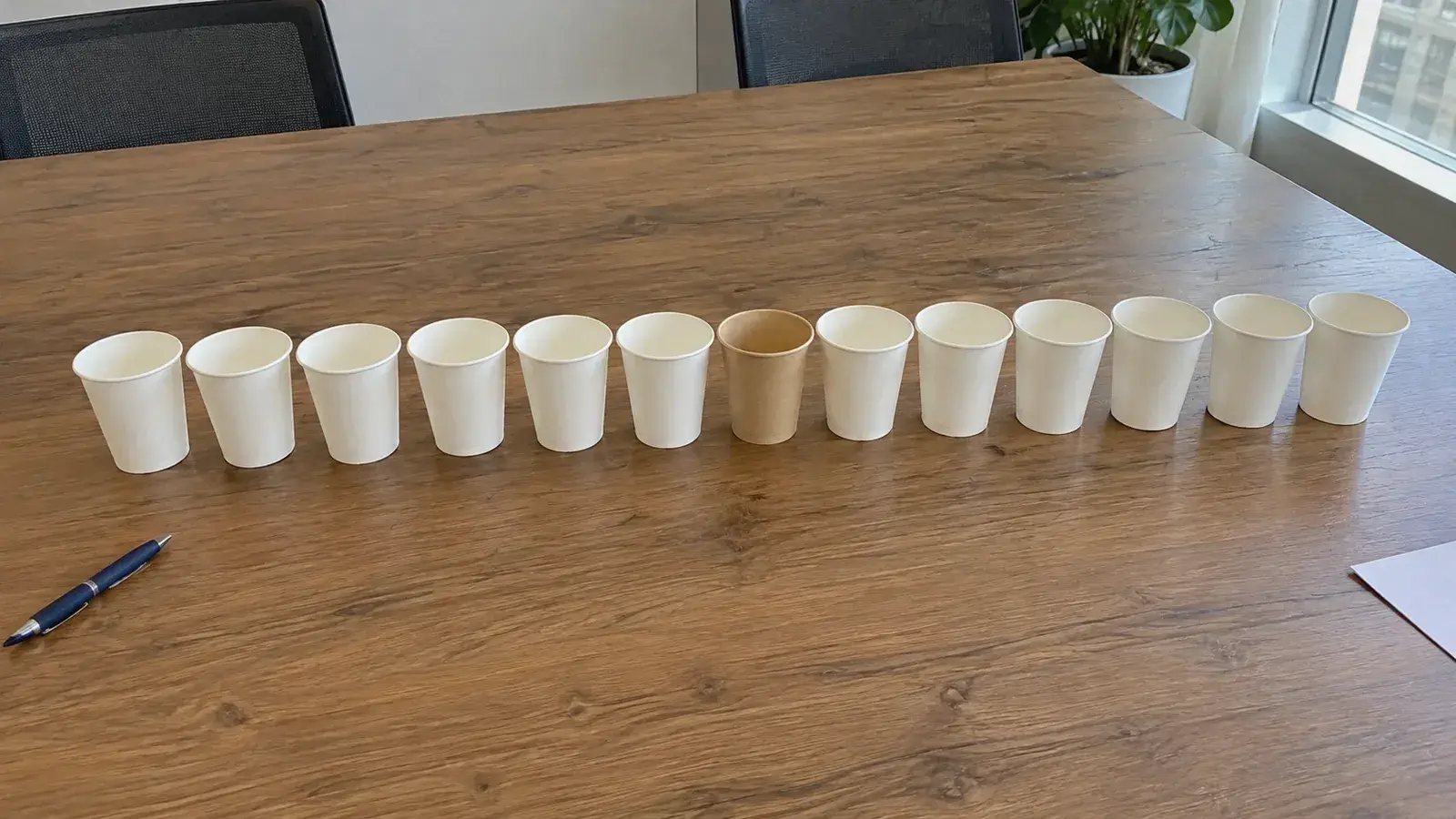 會議桌上並排一列白紙杯，只有一個牛皮紙杯不同，示意素材多卻集中在同一種格式